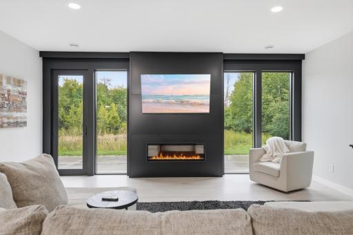 Dramatic fireplace is uniquely finished in matte black steel and encased by floor to ceiling custom windows, maximizing the extraordinary scenic backdrop.