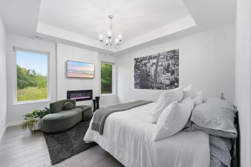 Romantic primary suite overlooking private backyard. Soaring tray-vault ceiling, all-season electric fireplace, Large crank out windows, custom blackout window treatments, solid-surface flooring and room for king-size furniture.