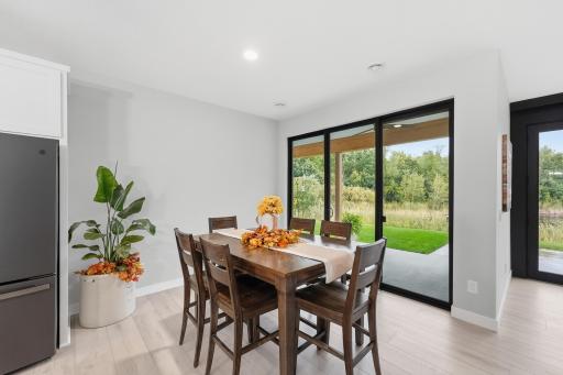 Dining Area — Sun-filled dining area opens directly to the covered patio, 9x8 patio door captures the natural backdrop, creating an effortless connection between indoor and outdoor living.