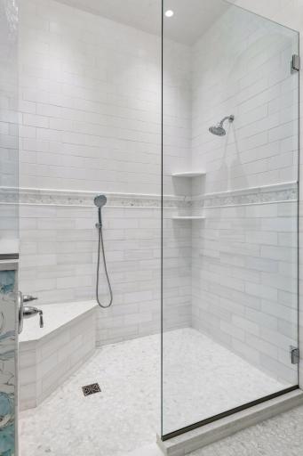 The large, tiled shower features a zero-entry threshold and built-in bench.