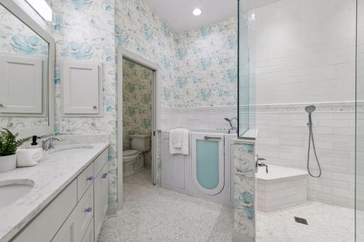The Primary Bathroom has been beautifully updated with heated tile flooring, designer wallpaper and a therapeutic bathtub.