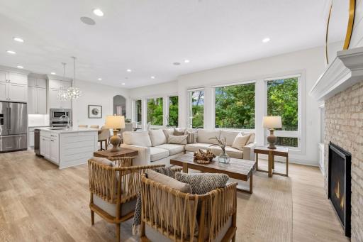 Walls of windows overlook the private backyard lined with mature trees.