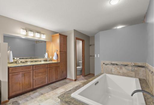 Primary bathroom has ceramic tile floors, double sink with quartz counters, soaking tub and walk in shower
