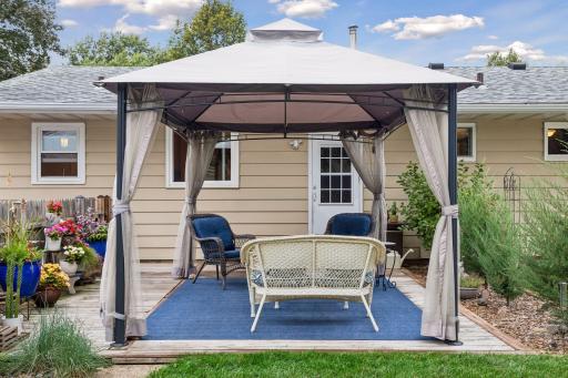 Fenced-in backyard featuring a Wood patio with a metal canopy for shade and a raised bed garden.