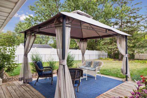 Fenced-in backyard featuring a Wood patio with a metal canopy for shade and a raised bed garden.