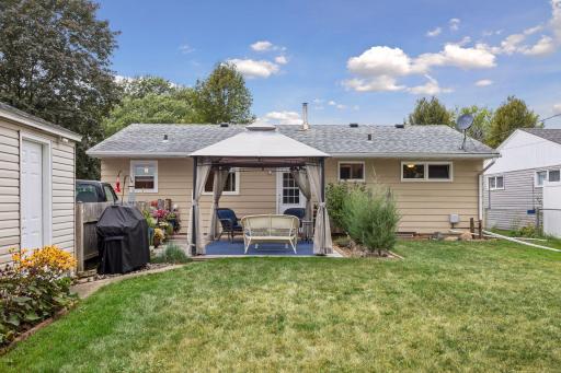 Fenced-in backyard featuring a Wood patio with a metal canopy for shade and a raised bed garden.