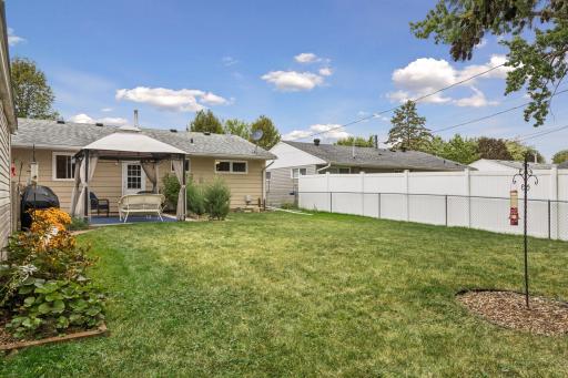 Fenced-in backyard featuring a Wood patio with a metal canopy for shade and a raised bed garden.