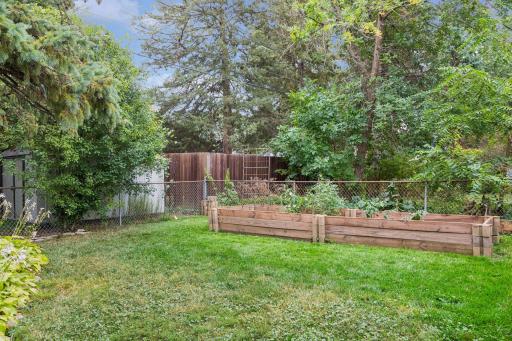 Fenced-in backyard featuring a Wood patio with a metal canopy for shade and a raised bed garden.