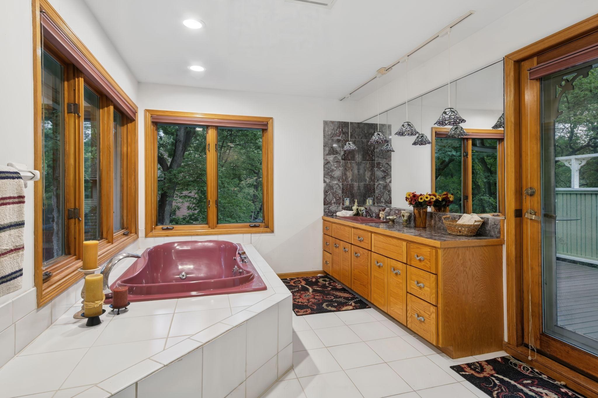 Owner's Bathroom Featuring a Jetted Tub and Rosso Levanto Style Marble Vanity