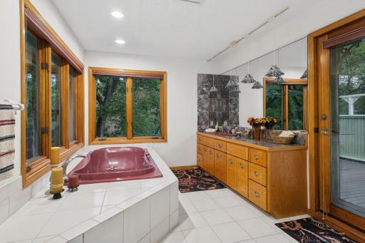Owner's Bathroom Featuring a Jetted Tub and Rosso Levanto Style Marble Vanity
