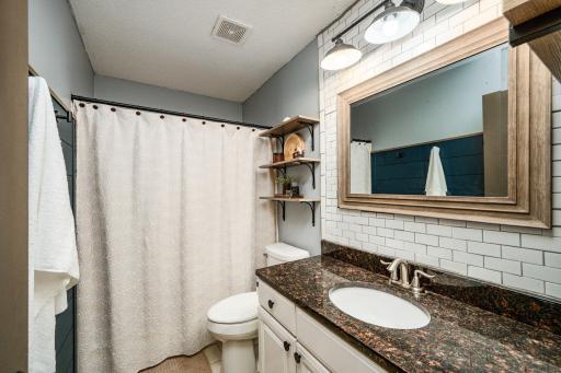 The main-level full bathroom includes a granite countertop, tile floor, and tile surround.