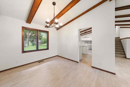 Light-filled formal dining room with vaulted, beamed ceiling and views of the backyard