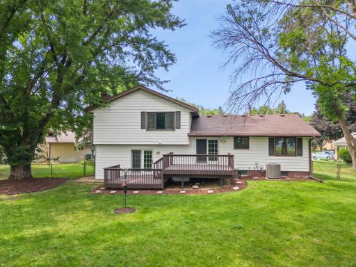 Spacious backyard with mature trees, lawn, fencing, and a raised deck for outdoor relaxation and entertaining