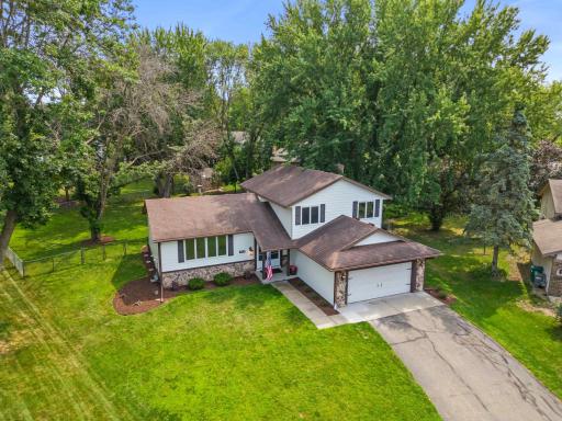Elevated front view showcasing the home's multi-level design, attached two-car garage, mature landscaping, and tree-lined setting