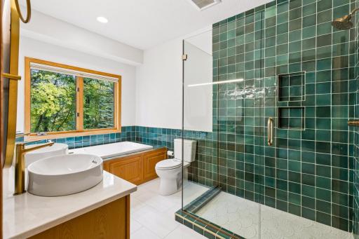 Renovated primary bath with a custom designed walk-in shower; gorgeous tile and minimal glass walls.