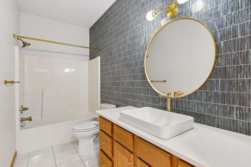 Main floor full bath with amazing wall of tile - just gorgeous! New countertop, vessel sink, fixtures, mirror and lighting.