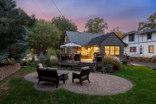 Beautiful paver patio steps down from large deck at the back of the home