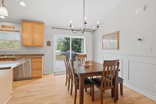 Dining area with board and batten wainscoting, updated lighting and sliding doors to deck.
