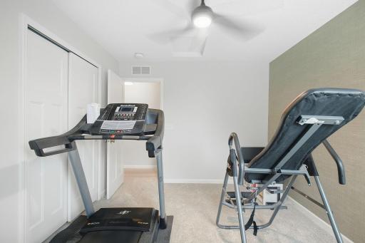 Third bedroom on upper level with ceiling fan being used as an exercise room.