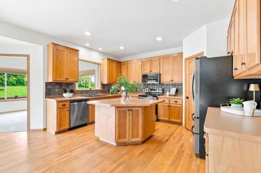 The beautifully appointed kitchen features stainless steel appliances, a center island, hardwood floors, and expansive workspace for cooking, gathering, and entertaining.