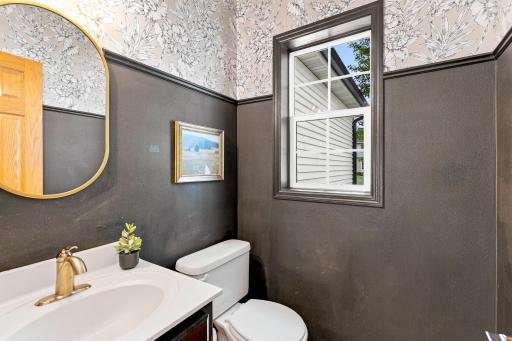 Stylish main-level powder bath featuring designer wallpaper, updated fixtures, and a window that fills the space with natural light.