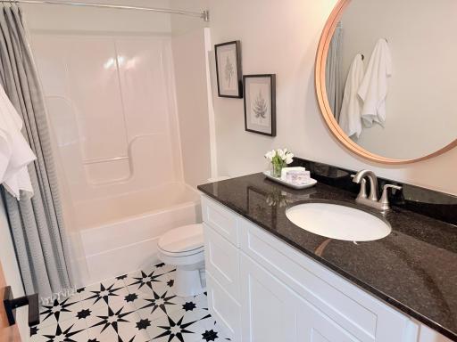 The spacious upper-level full bathroom is thoughtfully designed to comfortably serve the home's three secondary bedrooms. It features a large single-sink vanity with granite