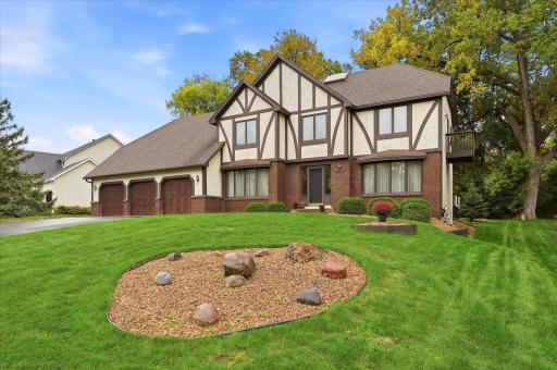 Classic curb appeal with a stately brick and stucco exterior, expansive driveway, three-car garage, and a beautifully maintained lawn.