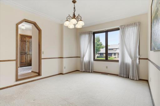 Bright formal dining room features a tray ceiling, large front-facing window, and classic wood trim.