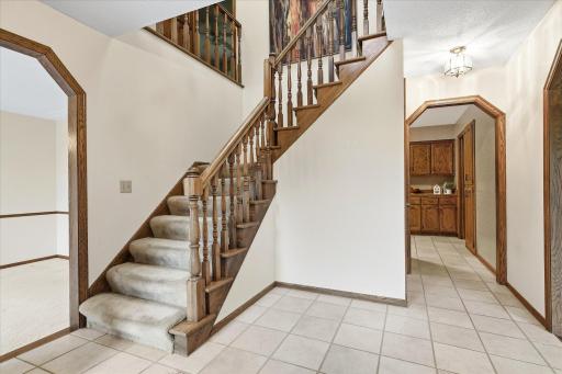 Spacious entry showcases rich woodwork, tile flooring, and an open staircase, with easy access to the main-level living spaces.