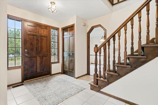 Welcoming foyer features tile flooring, a beautiful wood front door with sidelights, and a classic wood staircase leading to the upper level.