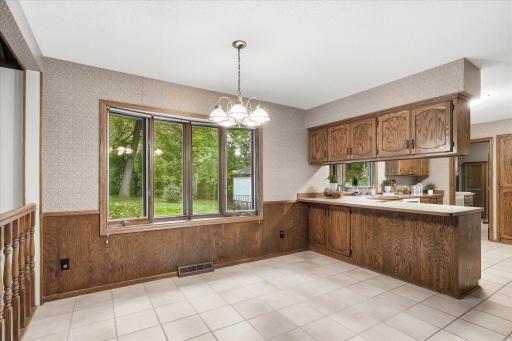Informal dining area features tile flooring, abundant natural light, extensive woodwork, and a breakfast bar connecting to the kitchen.