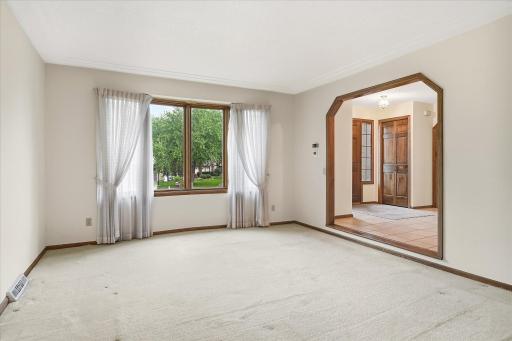 Main Level Living Room: Spacious and bright living room featuring neutral finishes, large front-facing windows that bring in plenty of natural light, and a wide opening to the foyer for an open, inviting feel.