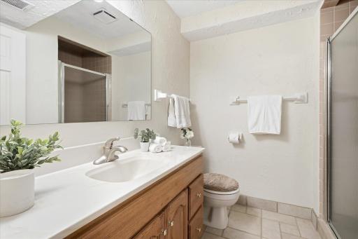 Convenient 3/4 bathroom features a spacious vanity, tile flooring, and a walk-in shower.
