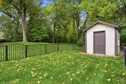 Expansive backyard features mature trees, a fenced dog run area, and a convenient storage shed.