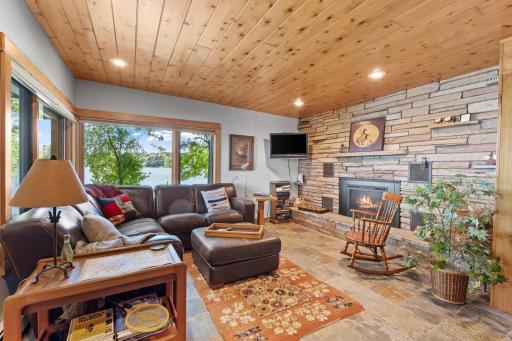 The lower-level family room has a stone fireplace and windows toward the lake.