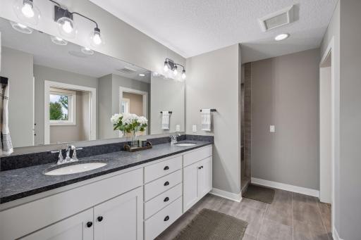 Primary bathroom with dual sinks, walk in shower with dual shower heads, and walk in closet