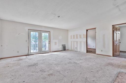 Living room with double doors to the rear of the home., Bedroom door to the right.
