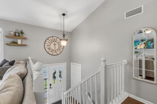 Foyer features open staircase that offers enameled railings and maple hardwood treads. Vaulted ceilings