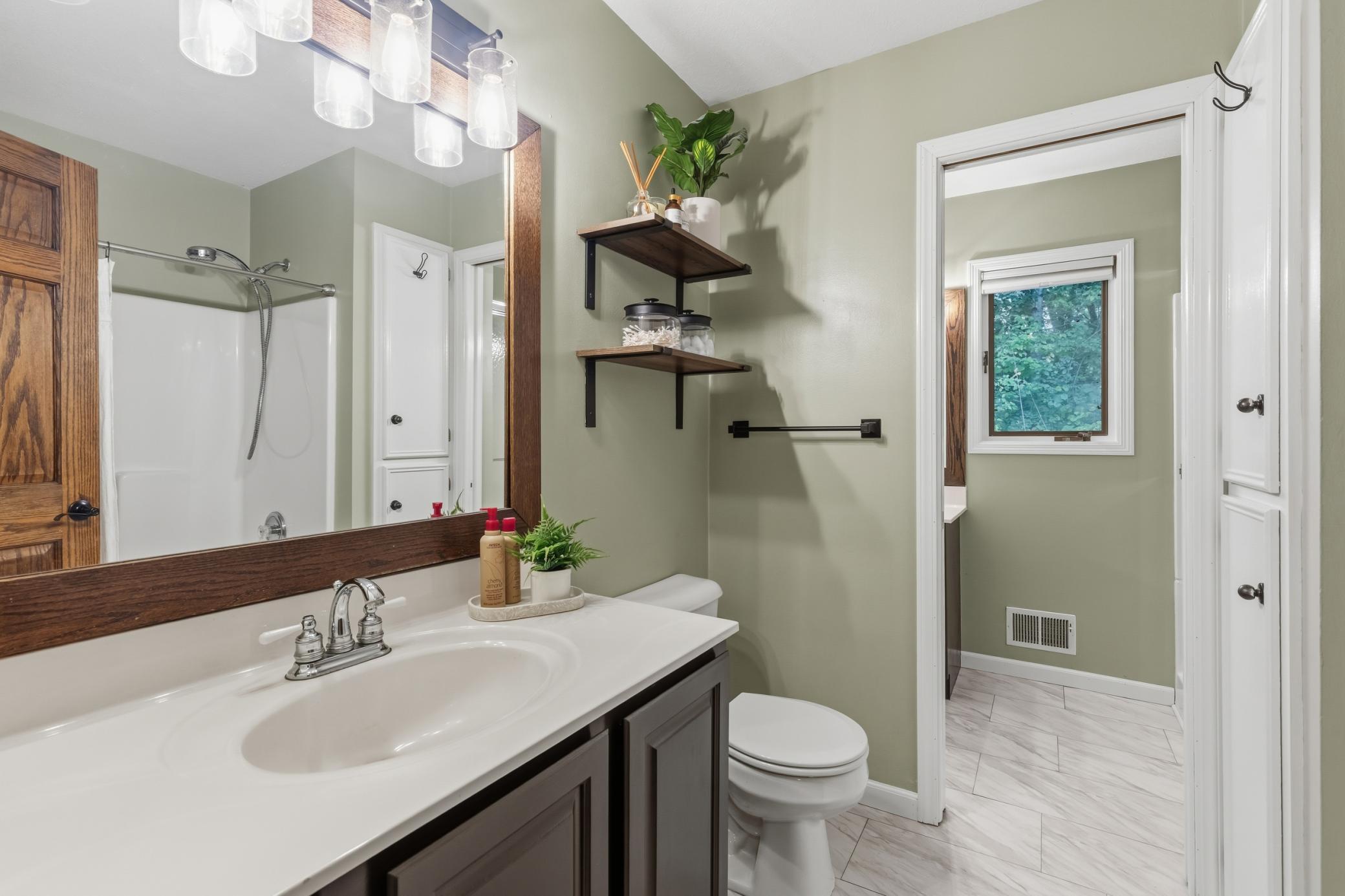 Full Walk-Through Bathroom offers a main bath that features a tub, linen closet, enameled vanity cabinet and laminate tile floors.