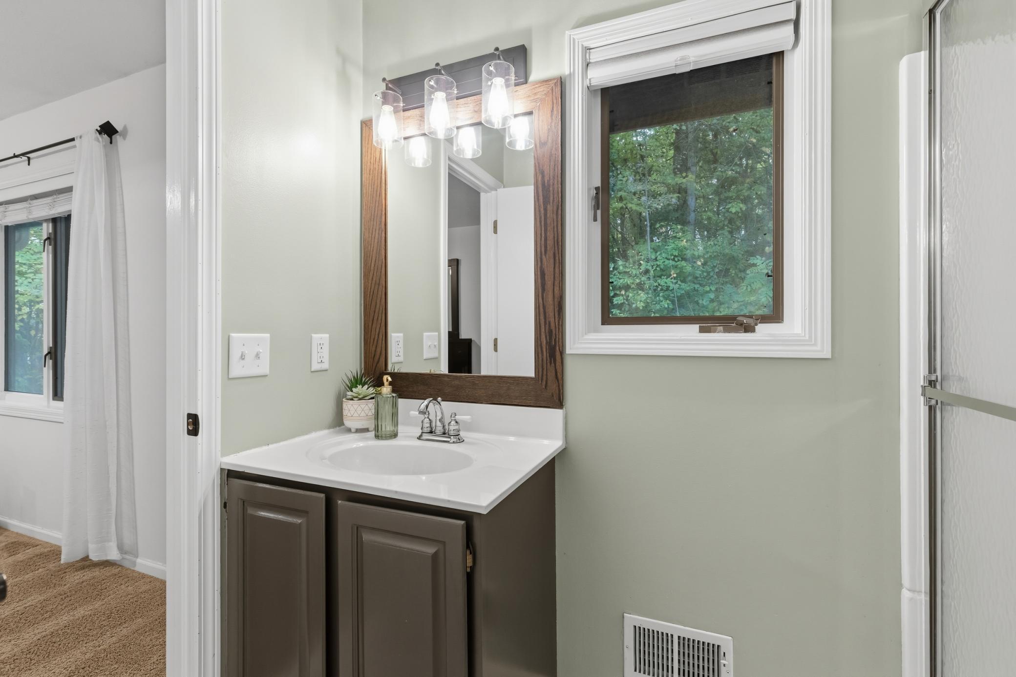 Pocket door access to the additional bath which includes a shower with glass doors, enameled vanity cabinet, natural light and access to the master bedroom!