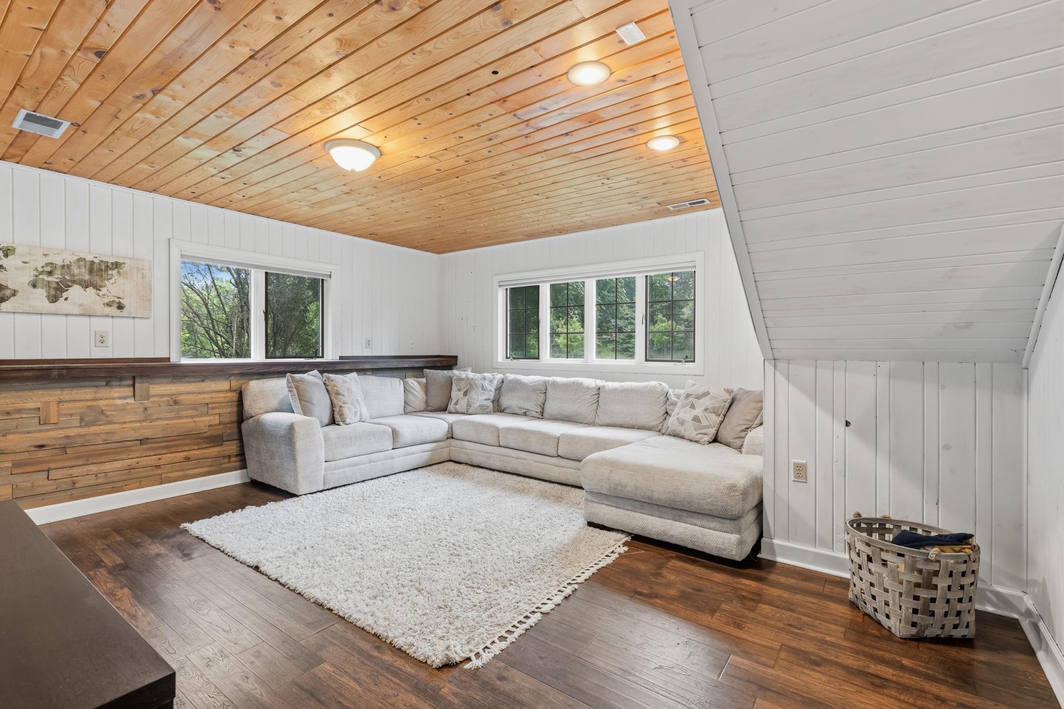 The Lower Level Family Room features wood paneled walls and ceilings, laminate flooring and offers a garage entry in a separate area