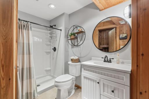 3/4 bathroom features partial wood paneled walls and ceiling, enameled vanity cabinet and ceramic tile flooring