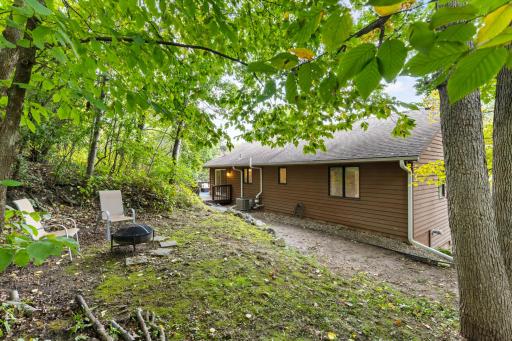 Mature landscape includes boulder retaining walls, majestic trees, mulched gardens and open area with fire pit!