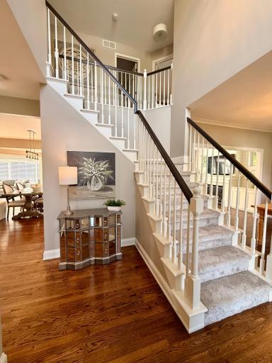 A warm and welcoming two-story foyer with beautiful hardwood floors, soaring ceilings and an open staircase that makes a wonderful first impression