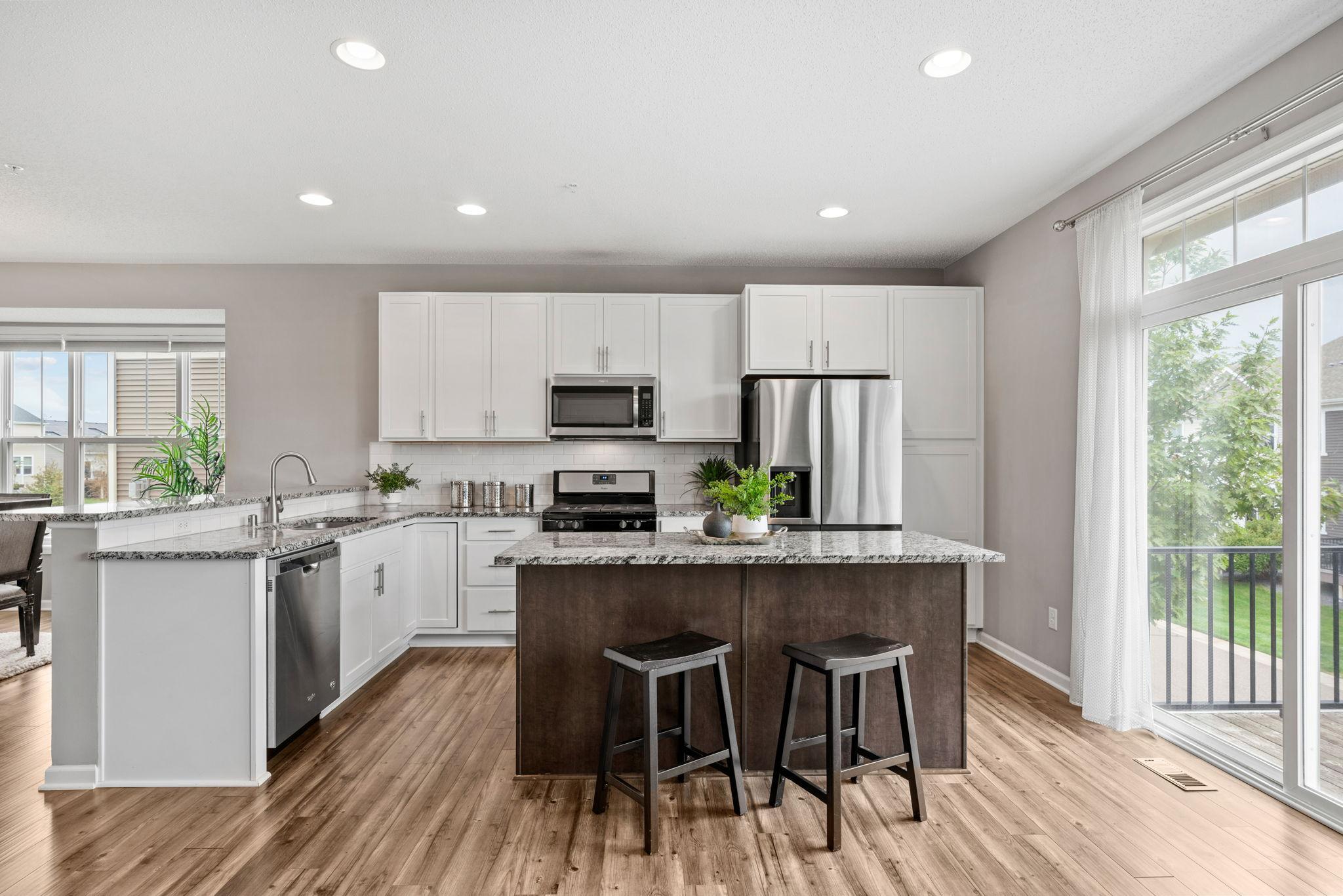 The kitchen sports granite counter tops and neutral backsplash for you to make it your own as well as an island with even more seating