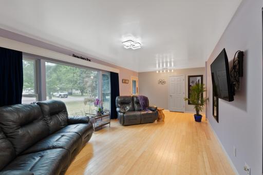Main living room with a large picture window, light wood floors, and plenty of space for seating