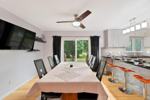 Dining area with ceiling fan and sliding patio door to the backyard, open to the kitchen breakfast bar