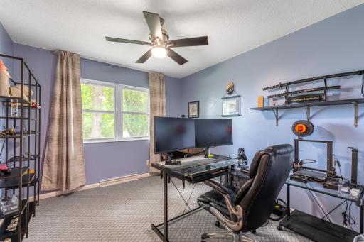 Bedroom with large window, ceiling fan, and carpet, currently set up as a home office