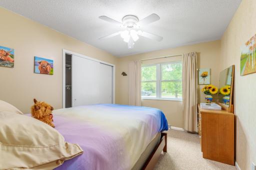 Bedroom with double-door closet, ceiling fan with light, and window for natural light