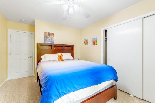 Bedroom with double-door closet, ceiling fan, and neutral carpet